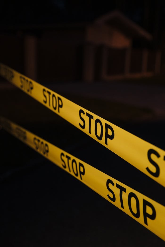 our-services-2 Yellow stop tape in a night crime scene setup, creating a tense atmosphere.