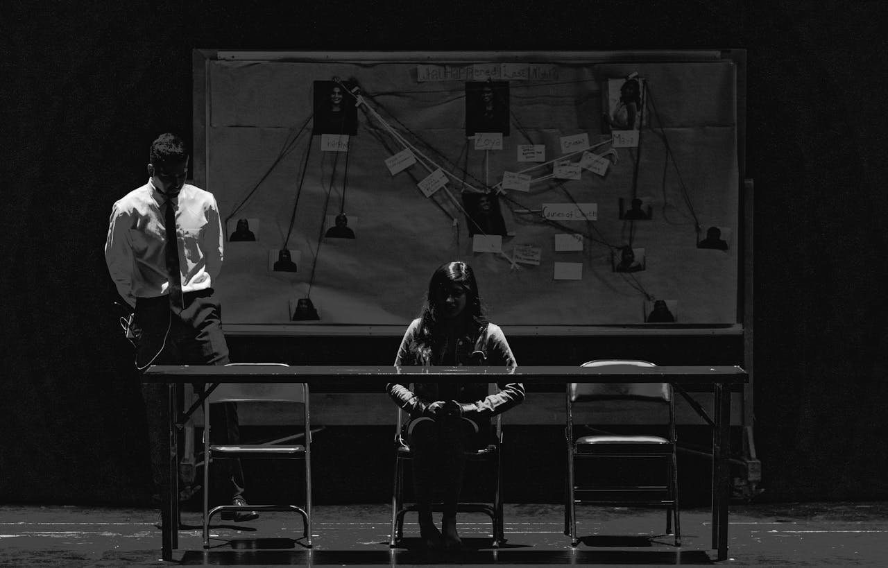 our-services-1 Black and white scene depicting a tense interrogation with suspect and investigator.