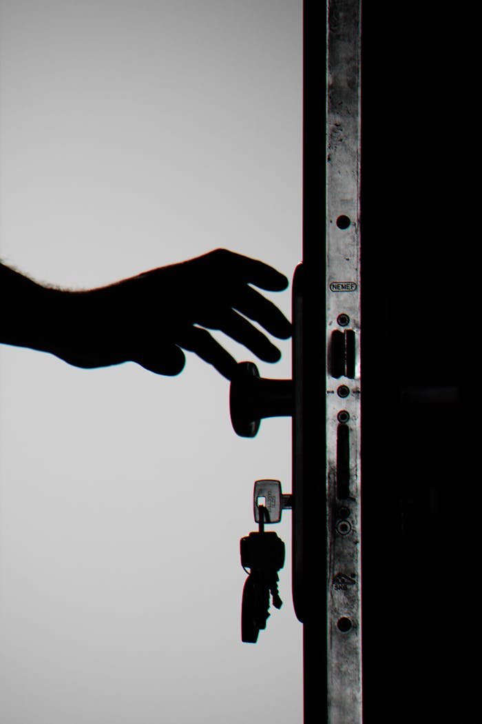 hero-img-02 Silhouette of a hand about to open a door with keys in lock, symbolizing security.